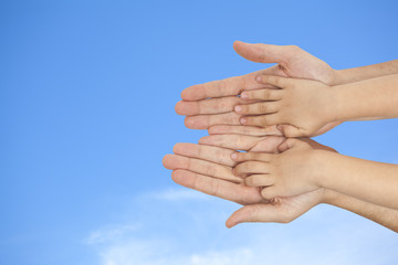 father and son holding hands on sky background