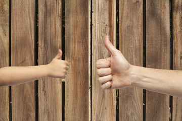 father and son hands giving like on wooden background