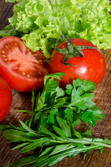 Juicy tomatoes with green-stuff on wooden table