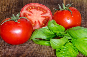 Juicy tomatoes with green-stuff on wooden table