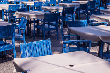 Rows of blue tables and chairs at a beach side eatery