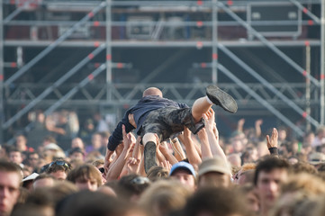 A young man raised by the crowd during a concert - obrazy, fototapety, plakaty