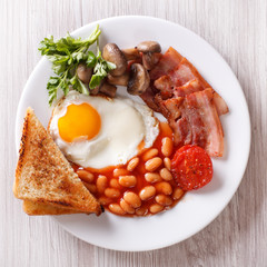 Fried egg with bacon, beans and toast top view closeup
