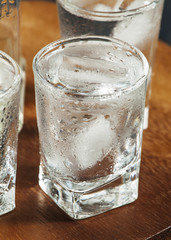 Clold fresh water with ice in a glass on a dark background in vi