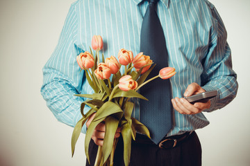 Businessman dials phone number, holding tulips