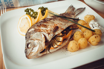 Grilled carp fish with rosemary potatoes and lemon