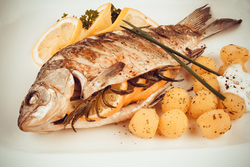 Grilled carp fish with rosemary potatoes and lemon