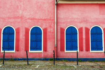 Rote alte Wand mit blauen Fenstern