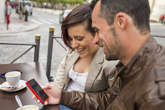 Couple in outdoors bar terrace touching smartphone