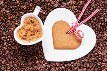 Heart shaped cup and cookie on coffee beans background