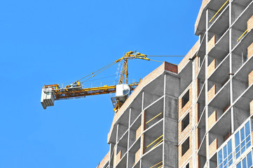 Crane and building construction site against blue sky