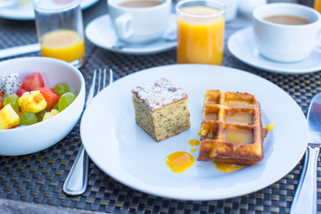 Delicious waffles, cake, coffee and juice served for breakfast
