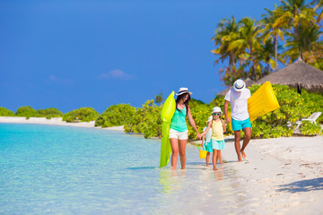 Happy beautiful family on white beach with air mattresses 