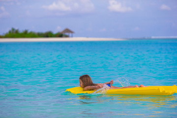 Adorable little girl on air inflatable mattress in the sea