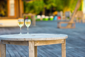 Two glasses of tasty white wine at sunset on wooden table