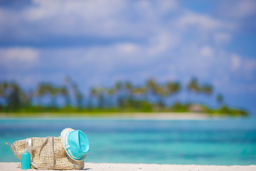 Straw bag, blue hat, sunglasses and sunscreen bottle on tropical