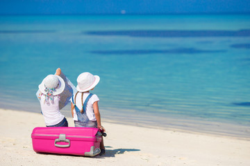Fototapeta na wymiar Little girls with big suitcase and map at tropical beach