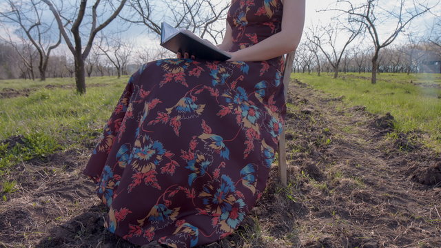 Woman in dress sitting on Chris middle of spring garden and