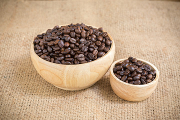 Coffee beans in wood cup on gunny sack