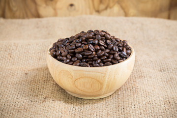Coffee beans in wood cup on gunny sack