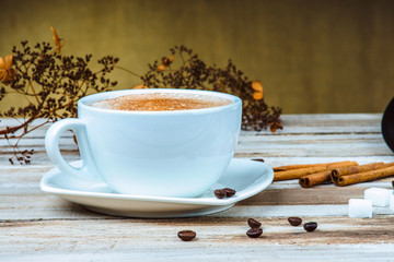 Coffee cup with cinnamon and sugar on a wooden table