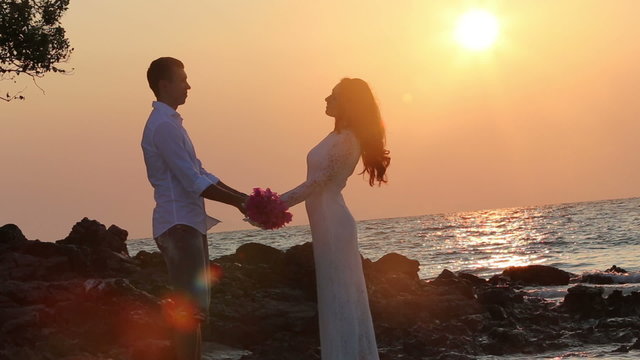 bride with bouquet comes to groom against rising sun	