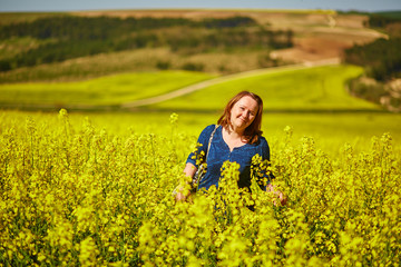 Fototapeta premium Young woman in rapeseed fields
