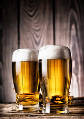 Two glasses of light beer with foam