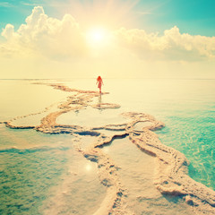 Silhouette of young woman walking on Dead Sea
