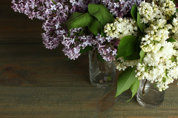 Lilacs in a glass on a wooden background