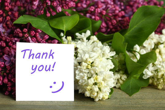 Thank you note and lilac flower on the wooden table