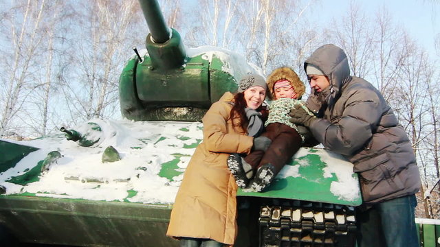 Family near the battle tank in the winter

