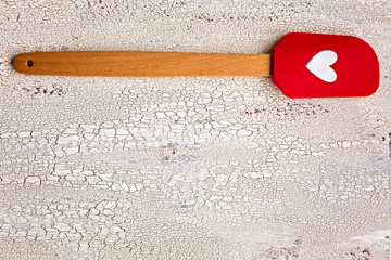 Wooden and silicon red  kitchen spatula with heart on wooden bac