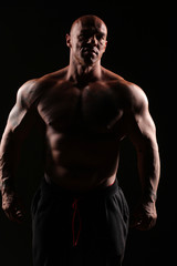 Fototapeta na wymiar muscular bald man posing on a black background