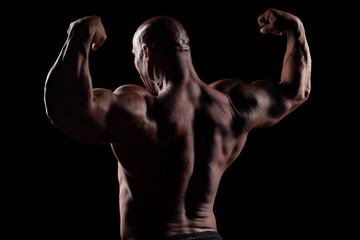 Obraz na płótnie Canvas back view on muscular bald man posing on a black background
