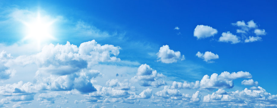 Fototapeta Fototapeta Białe, pojedyncze chmury i jaskrawe słońce w niebieskim niebie panoramiczna