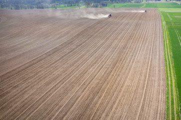 Fototapeta premium Aerial view of the tractor harrowing the field