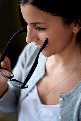 Close up of woman smiling and holding glasses.