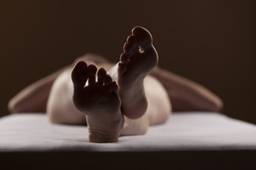 well-groomed female feet on a white bed in a dark room