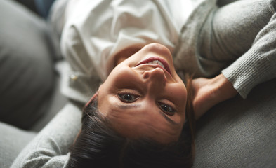 Woman laying on couch looking up smiling.