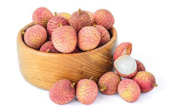 Ripe lychee fruit in wooden bowl against white background
