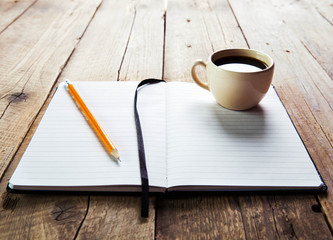notebook pen and cup of coffee in wood table