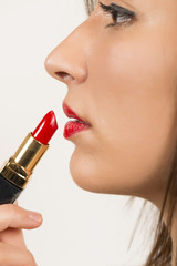 Close up portrait of beautiful woman applying red lipstick
