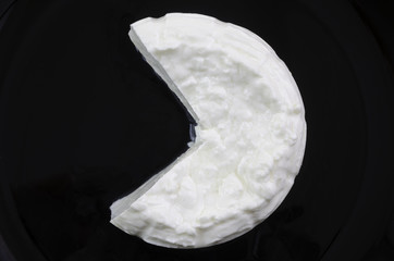 Fresh cheese over black dish.