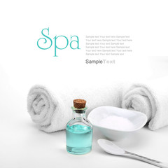 Spa concept. Blue oil, sea salt and towels, isolated on white.