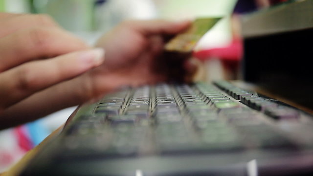 Man buying with credit card, using computer keyboard