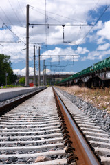 Fototapeta premium Rails and railway sleepers with clouds in a bright blue sky