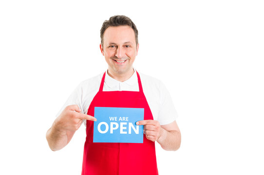 Friendly supermarket employee holding open sign