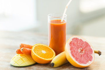 close up of fresh juice glass and fruits on table