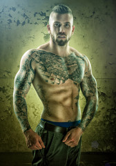 Tattoo, unique muscle-building man, standing of the wall